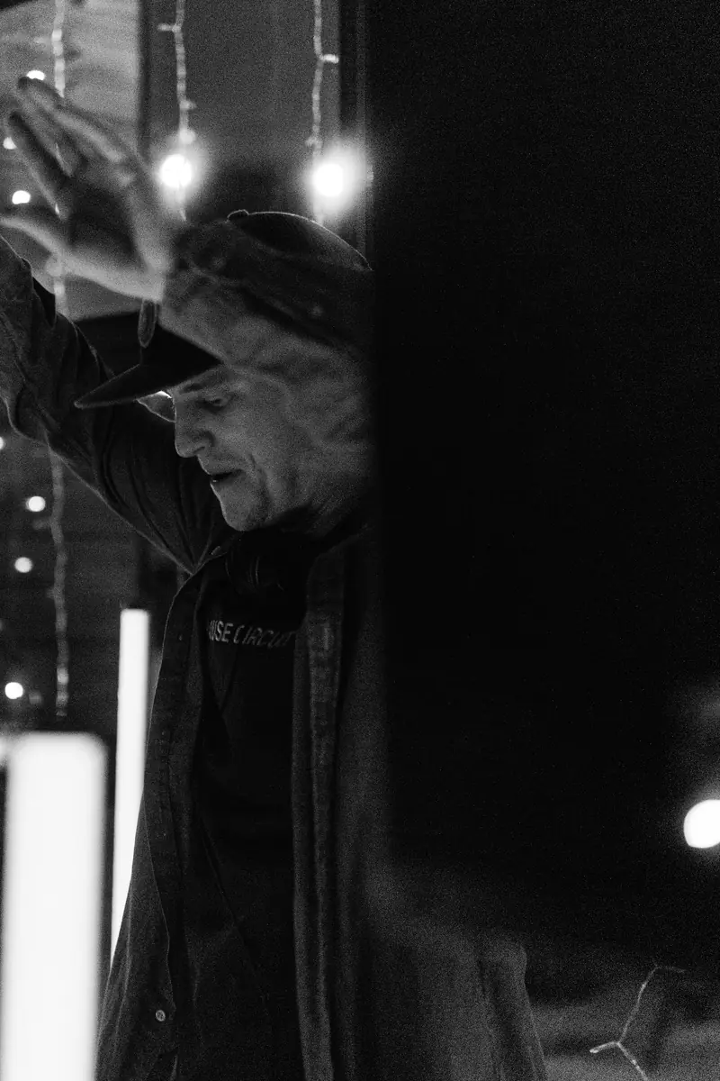 Hands up under the string lights, in black and white